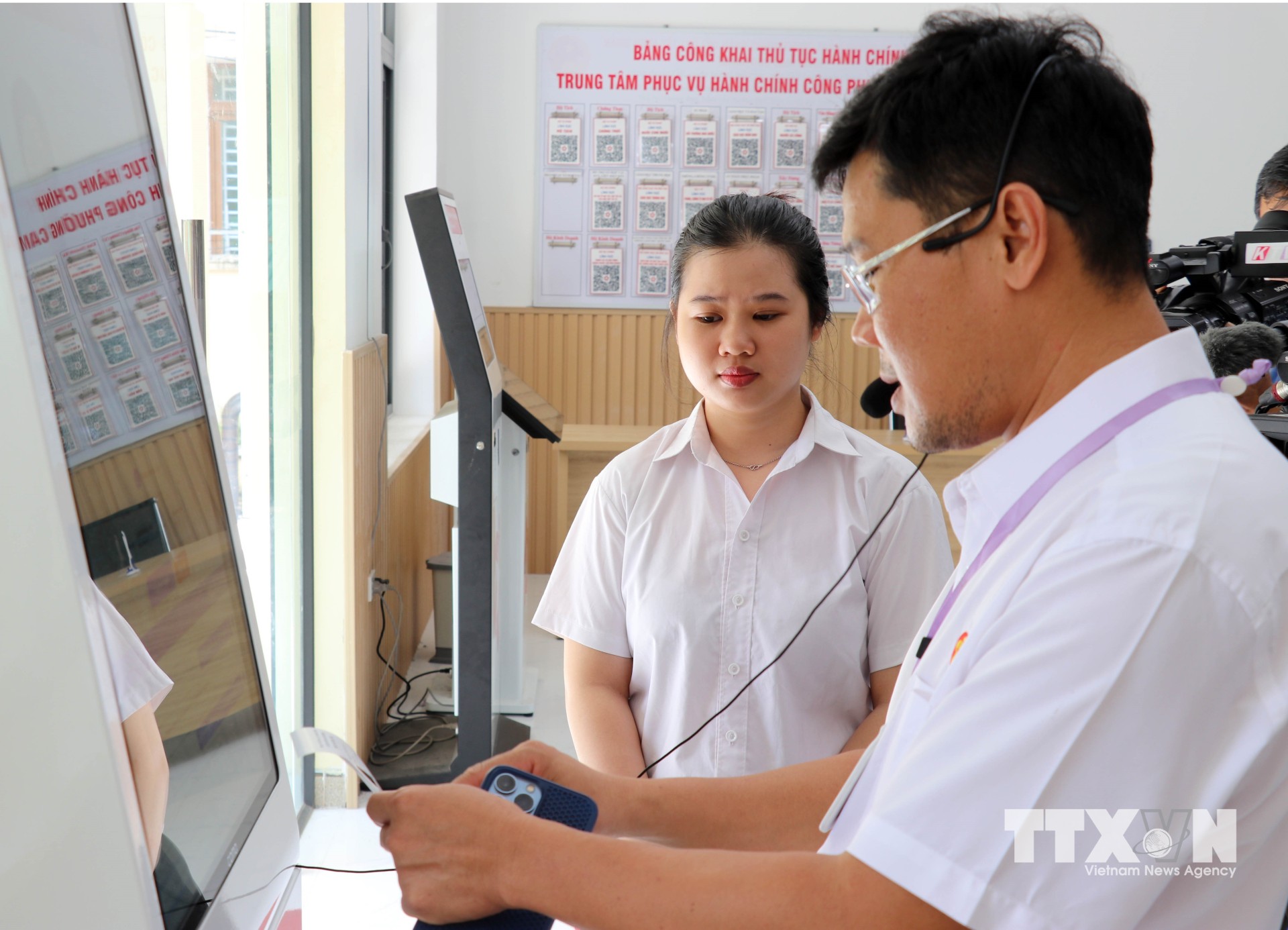 Lãnh đạo Trung tâm Phục vụ hành chính công phường Cam Ranh hướng dẫn nhân viên tư vấn sử dụng công nghệ hỗ trợ giải quyết thủ tục hành chính cho người dân. (Ảnh: Công Thử/TTXVN)